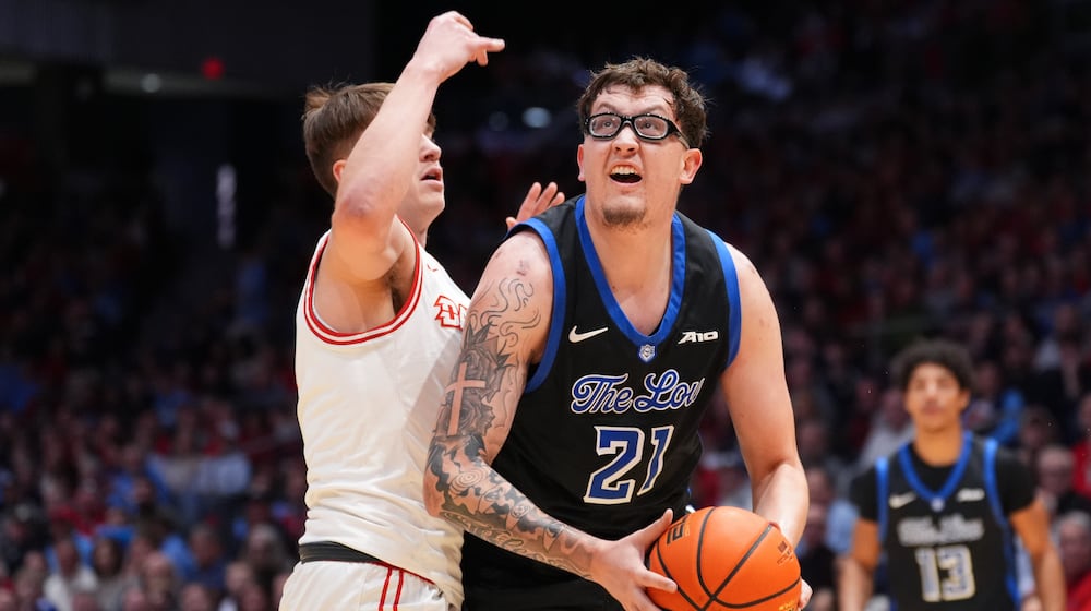 Saint Louis' Robbie Avila (21) spins toward the basket as Dayton's Jordan Derkack (4) defends during the first half of an NCAA college basketball game, Tuesday, Feb. 24, 2026, in Dayton, Ohio. (AP Photo/Kareem Elgazzar)