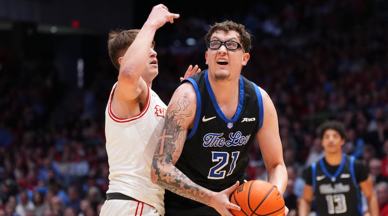 Saint Louis' Robbie Avila (21) spins toward the basket as Dayton's Jordan Derkack (4) defends during the first half of an NCAA college basketball game, Tuesday, Feb. 24, 2026, in Dayton, Ohio. (AP Photo/Kareem Elgazzar)
