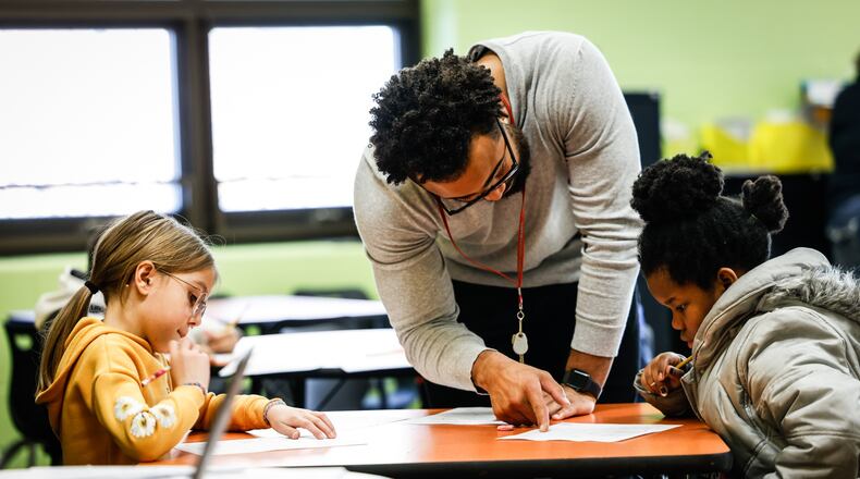 Third-grade tutor Tyree Kinnel helps Arayna Ruble, left, and Brooklynn Guy at Charles Huber Elementary School Tuesday, Feb, 15, 2022. Huber Heights is one of two districts using additional teachers to help kids catch up on learning loss from the pandemic. JIM NOELKER/STAFF
