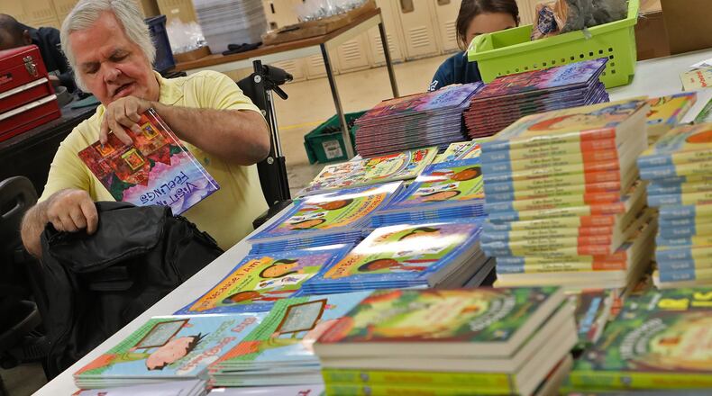 Jack Sharp, an employee at TAC Industries in Springfield, fills bags with childrens books for the Books to the Rescue program. TAC, which employs adults with disabilities, stocks Books to the Rescue bags with books and plush toys, then ships bags to participating agencies. BILL LACKEY/STAFF