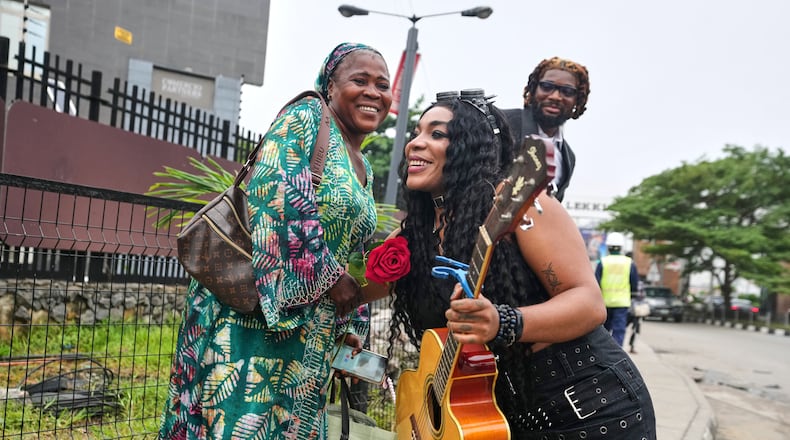 Nigerian rock musician Bianca "Clayrocksu" Okorocha, accompanied by Daniel Onyemachi-Chiweolu, popularly known as Machigold, hugs a woman after giving her a single-stem rose and crooning love songs ahead of Valentine's Day in Lagos, Nigeria, Tuesday, Feb.10, 2026. (AP Photo/Sunday Alamba)