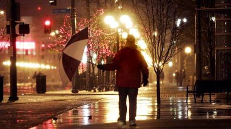 People in Dayton, including Paul Ward who walks along Main Street, contend with rain and ice on some sidewalks and roadways early Friday morning, but a predicted accumulation of overnight snow never materialized.