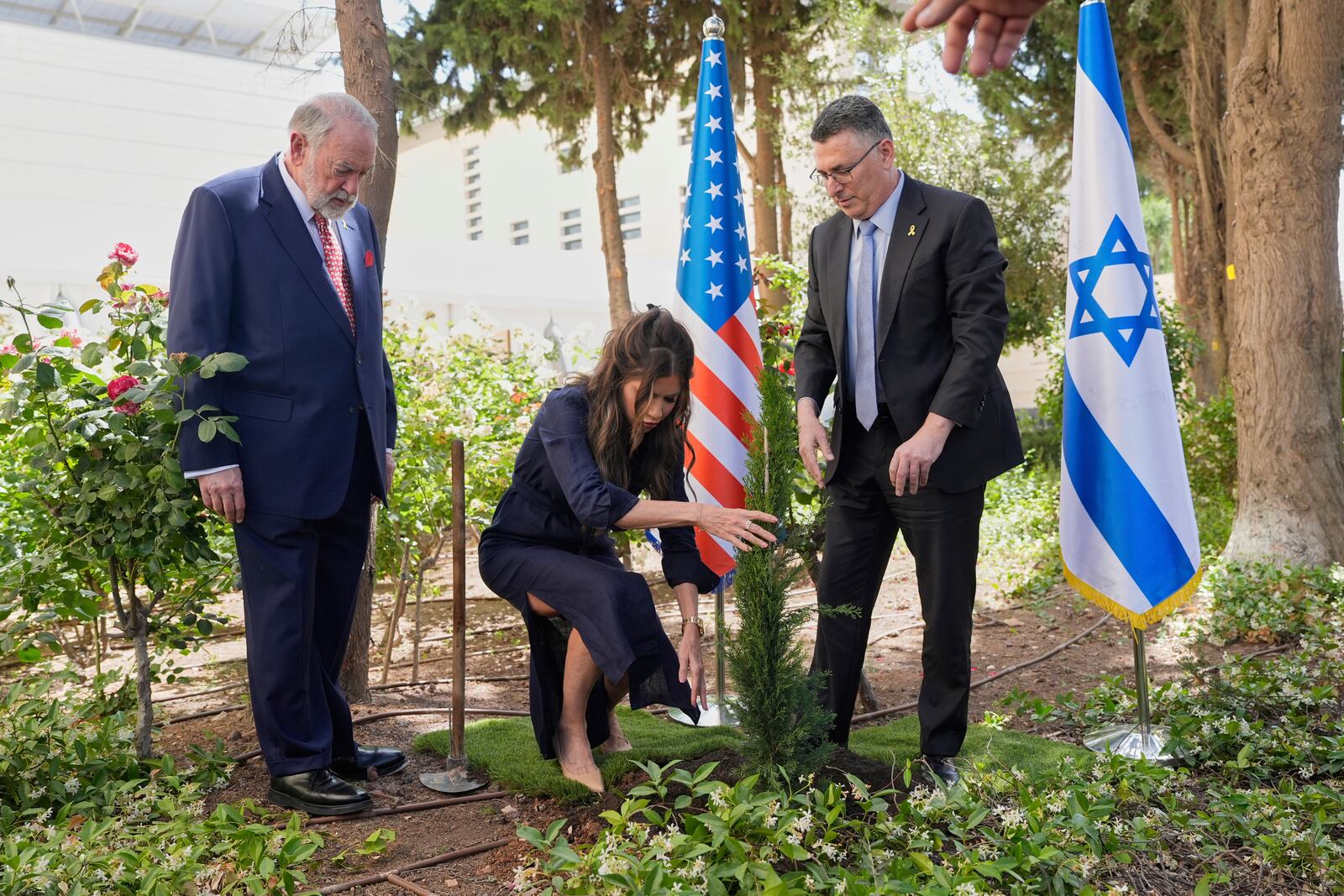 U.S. Homeland Security Secretary Kristi Noem, center, and Israel's Foreign Minister Gideon Sa'ar, right, plant a tree as U.S. Ambassador to Israel Mike Huckabee looks on, in Jerusalem, Monday, May 26, 2025. (AP Photo/Alex Brandon, Pool)