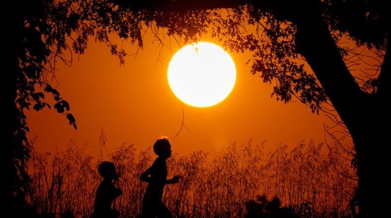 FILE - People are silhouetted against the sky at sunset as they run at Shawnee Mission Park, Sept. 26, 2024, in Shawnee, Kan. (AP Photo/Charlie Riedel, File)