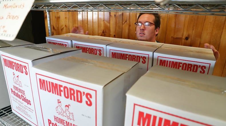Cody Pack, an employee at Mumford’s Potato Chips, stocks a shelf with boxes of the chips Tuesday. BILL LACKEY/STAFF