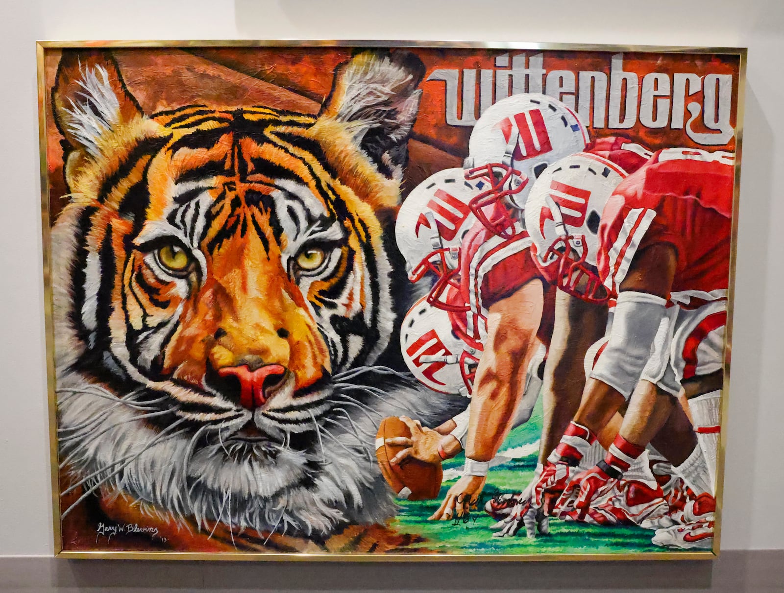 Gary Blevin's painting of Wittenberg University's football team hangs on a wall in a room of Blevin's art gallery on Thursday, December 18, 2025, in Springfield. JOSEPH COOKE/STAFF