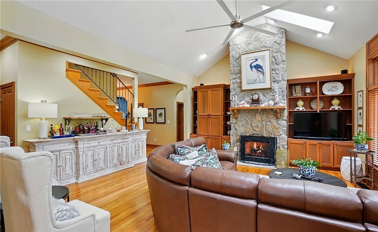 The great room has vaulted ceilings and skylights and a floor to ceiling stone fireplace.