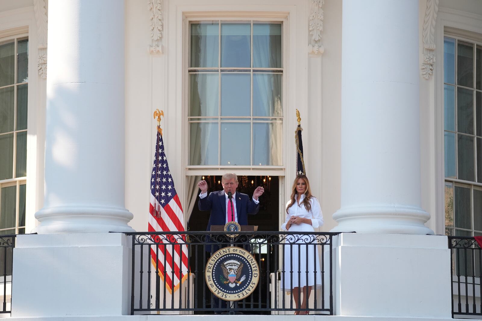 President Donald Trump speaks from the Blue Rom Balcony as first lady Melania Trump listens before he signs his signature bill of tax breaks and spending cuts at the White House, Friday, July 4, 2025, in Washington. (AP Photo/Evan Vucci)