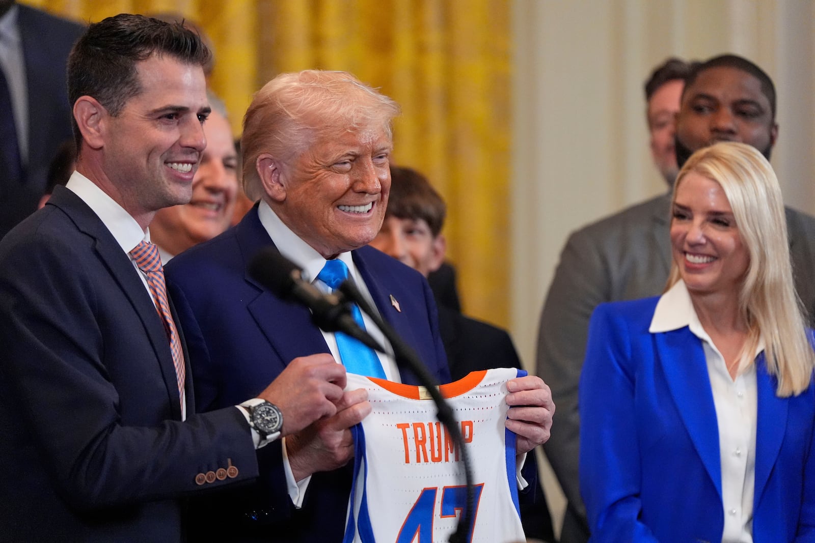 President Donald Trump and head coach Todd Golden poses with a jersey as Attorney General Pam Bondi watch as Trump hosts the 2025 NCAA Champion, University of Florida men's basketball team in the East Room of the White House, Wednesday, May 21, 2025, in Washington. (AP Photo/Julia Demaree Nikhinson)