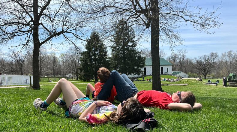 Mark Sieffert and his children, Poppy and Robbie, watch the total solar eclipse at Aullwood Audobon in Dayton on Monday, April 8, 2024. NATALIE JONES/STAFF