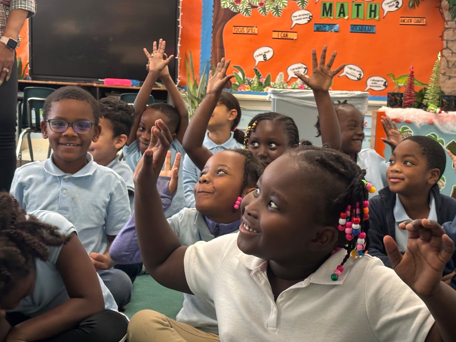 Students in the first grade class at St. Benedict the Moor elementary school raise their hands in a game just before lunch. Eileen McClory / Staff