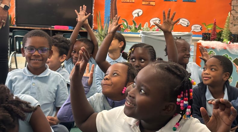 Students in the first grade class at St. Benedict the Moor elementary school raise their hands in a game just before lunch. Eileen McClory / Staff