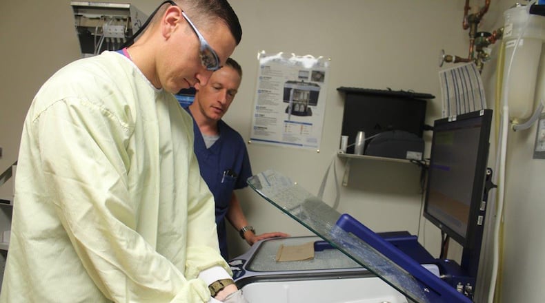 Lt. Col. Tristan Handler, 88th Medical Group chief of gastroenterology, checks medical technician Senior Airman Kaleb Specht, as Specht sanitizes the equipment used in the clinic.