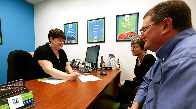 An IH Credit Union employee about checking accounts with a customer in March, 2016. Bill Lackey/STAFF