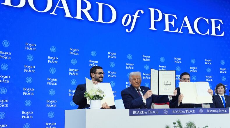 President Donald Trump, center, holds up a signed Board of Peace charter during the Annual Meeting of the World Economic Forum in Davos, Switzerland, Thursday, Jan. 22, 2026. (AP Photo/Evan Vucci)
