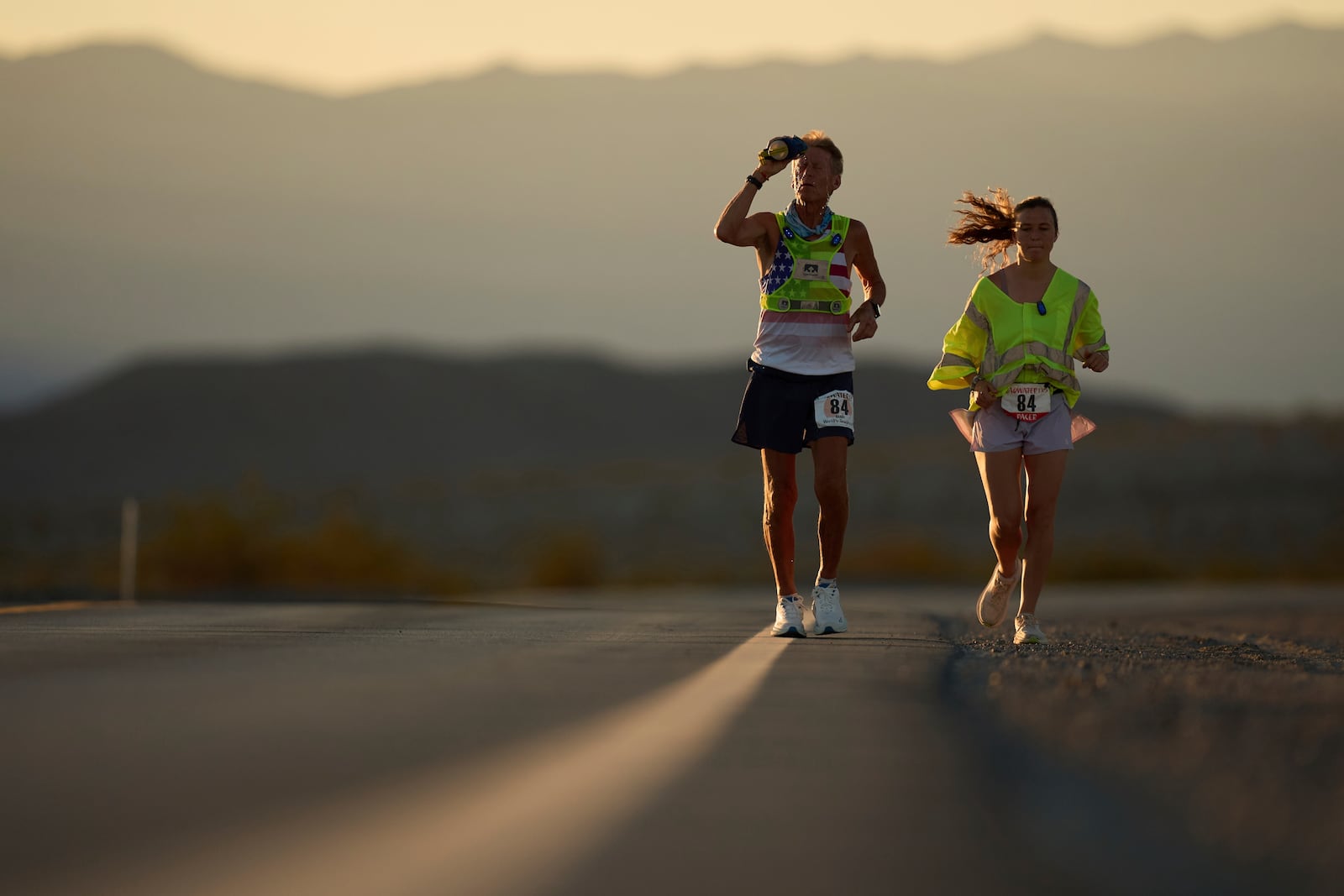 Danny Westergaard, left, cools of with water with pacing help from daughter Madison Westergaard as the sun rises during the Badwater 135 Ultramarathon, Tuesday, July 8, 2025, in Death Valley National Park, Calif. (AP Photo/John Locher)
