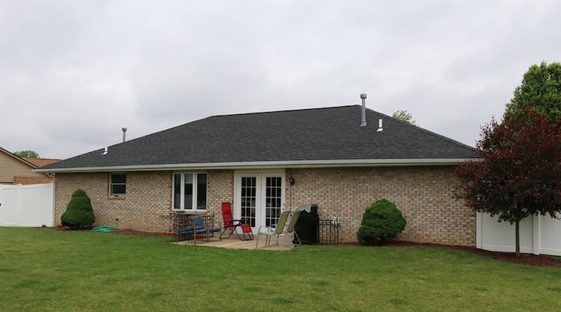 Patio doors open from the living and dining room to a concrete patio and a fenced back yard. White vinyl privacy fence surrounds the back yard, which includes a garden shed.