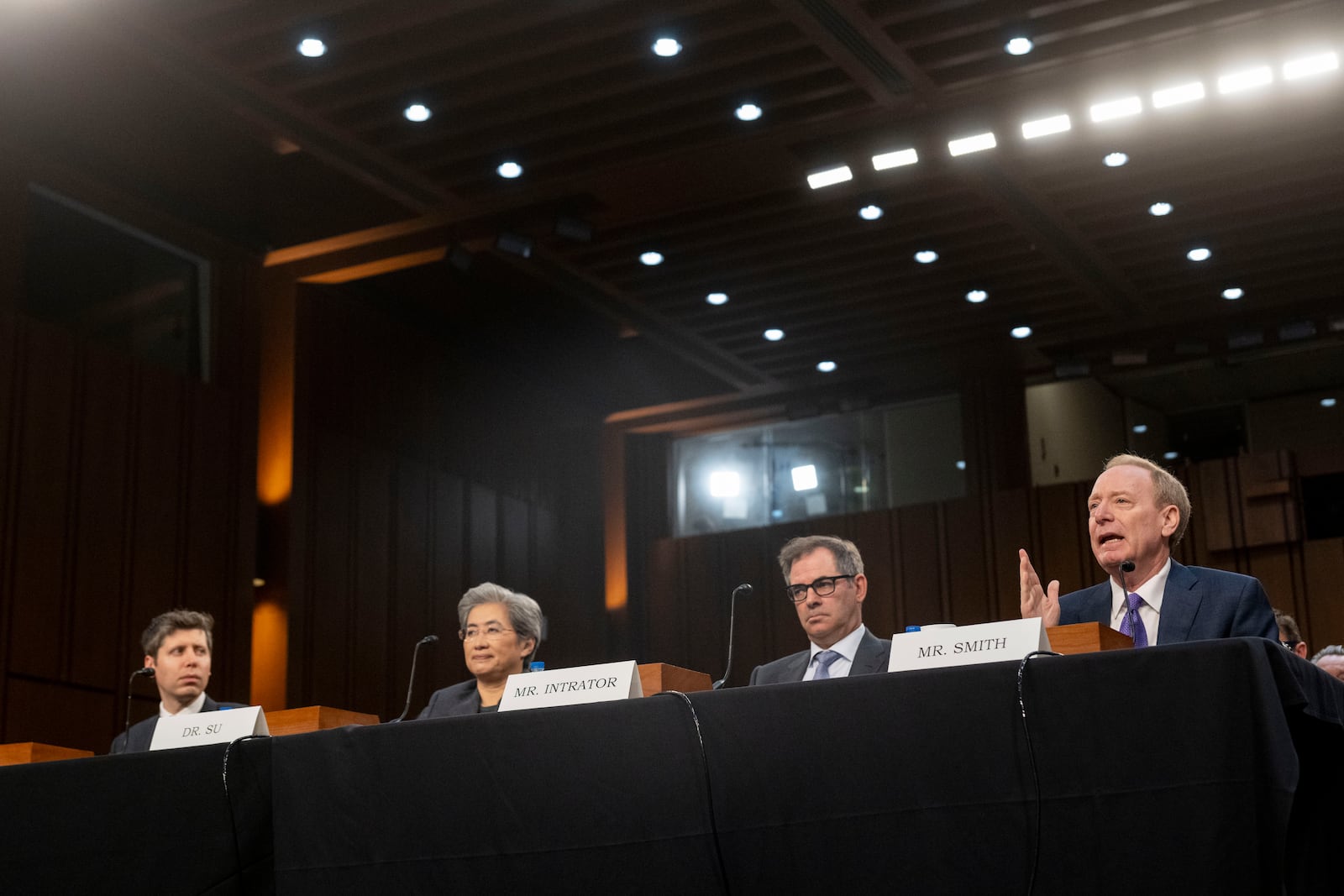 Brad Smith, Vice Chair and President, Microsoft Corporation, right, testifies before a Senate Committee on Commerce, Science, and Transportation hearing with, from left, Sam Altman, Co-Founder and Chief Executive Officer, OpenAI, Dr. Lisa Su, Chief Executive Officer and Chair, Advanced Micro Devices (AMD) and Michael Intrator, Co-Founder and Chief Executive Officer, CoreWeave, Thursday, May 8, 2025, in Washington. (AP Photo/Kevin Wolf)