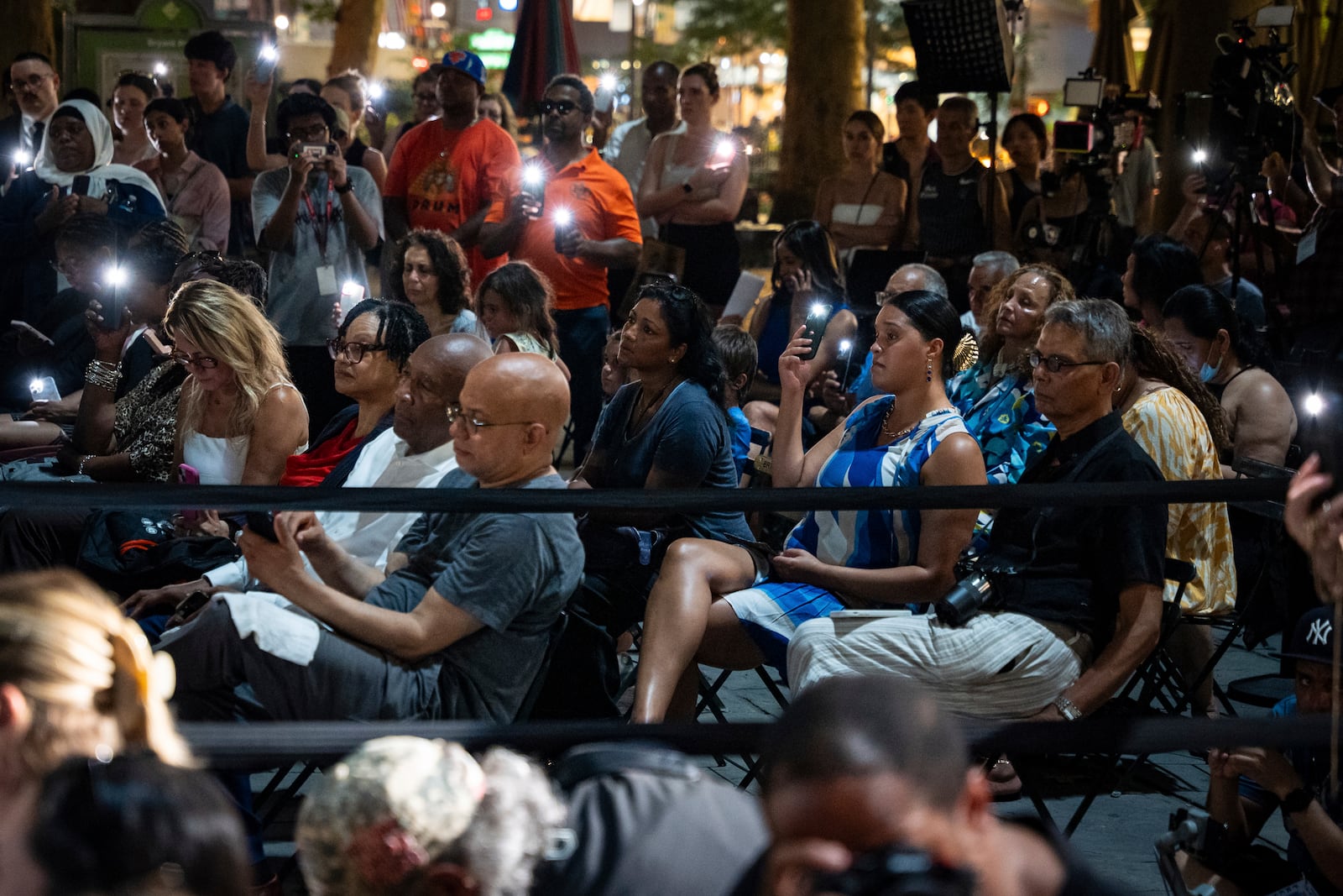 People raise their phone lights during the vigil for the victims killed in the previous day's shooting at 345 Park Avenue, including NYPD officer Didarul Islam, in Bryant Park, Tuesday, July 29, 2025, in New York. (AP Photo/Angelina Katsanis)