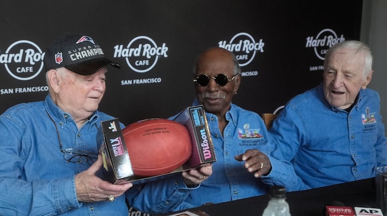 Don Crisman, left, holds up a Super Bowl LX football presented to he and friends Gregory Eaton, middle, and Tom Henschel, who have attended every Super Bowl football game by Wilson Sporting Goods, at a news conference at the Hard Rock Cafe in San Francisco, Friday, Feb. 6, 2026. (AP Photo/Jeff Chiu)