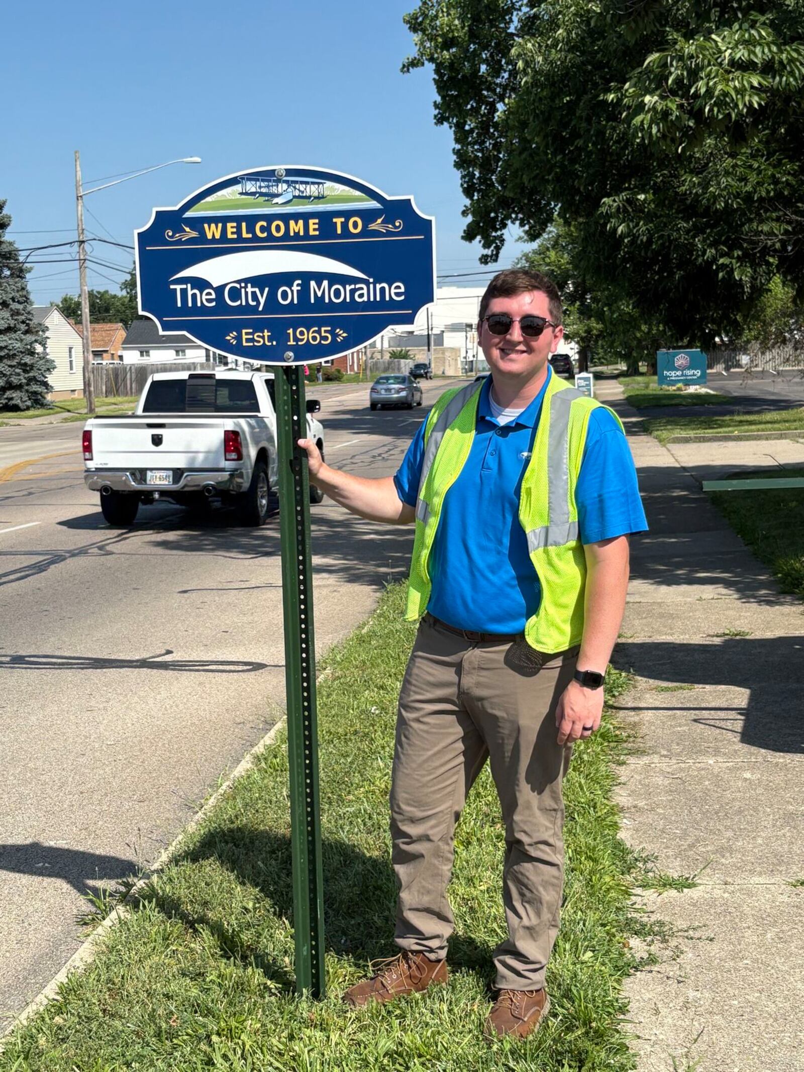 Moraine City Planner Nick Sorice stands next to one of 33 recently installed signs that welcome people to Moraine, celebrate the city's history and mark a milestone. The signs incorporate the Wright Seaplane and a reference to Moraine becoming a city in 1965. CONTRIBUTED