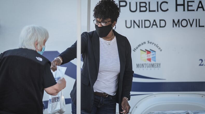 Montgomery County Public Health employee, Stacy Shern hands out free masks in the parking lot of the YMCA in Trotwood Thursday Nov. 12,2020. STAFF