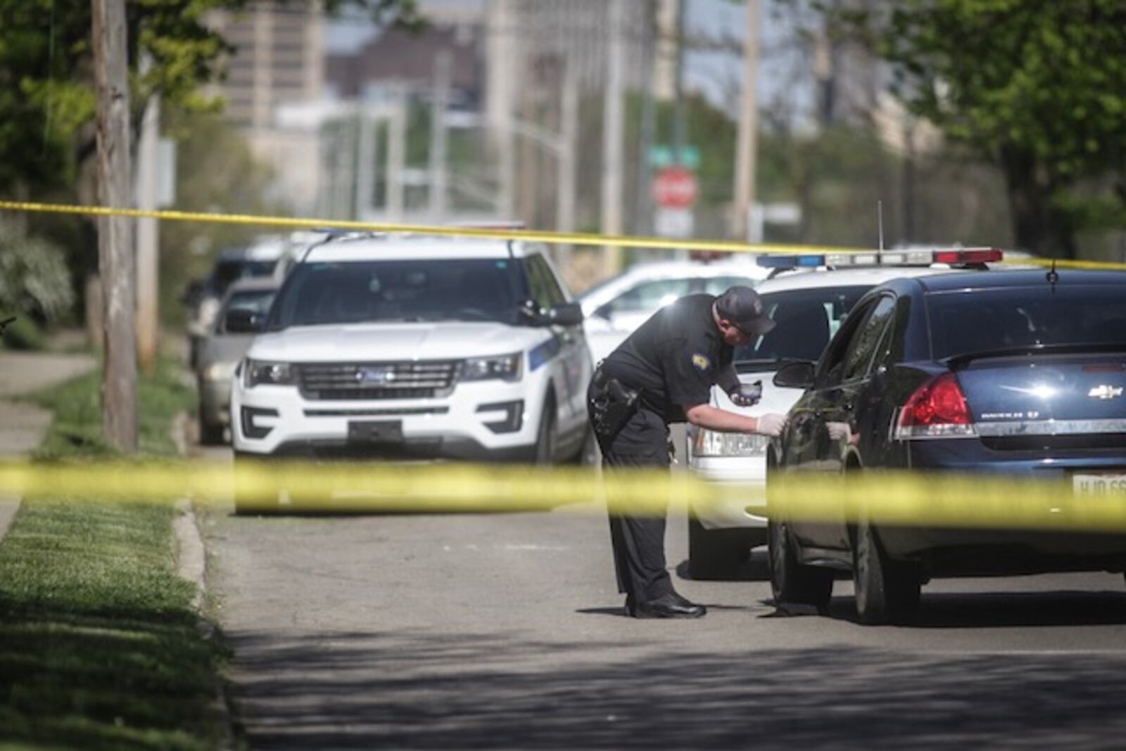 A Dayton police evidence technician examines a car found on West Second Street Tuesday, May 8, 2018.  The victim found wounded in that car told police he was shot elsewhere and drove to a relative's home on West Second Street. (Jim Noelker/Staff)