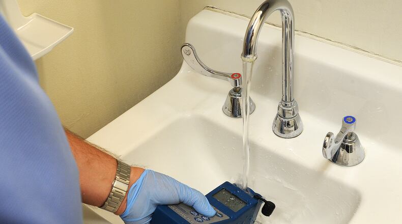 Doug Dolder, a Response Case Manager, for Solid Blend Water Management Solutions, test the water in a restroom at Southdale Elementary in Kettering for Legionella bacteria in 2020. MARSHALL GORBY\STAFF