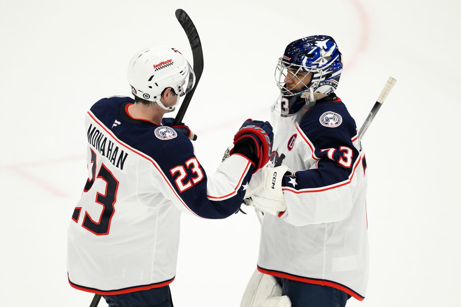 Columbus Blue Jackets goaltender Jet Greaves (73) celebrates with center Sean Monahan (23) after an NHL hockey game against the Washington Capitals, Sunday, April 13, 2025, in Washington. (AP Photo/Nick Wass)