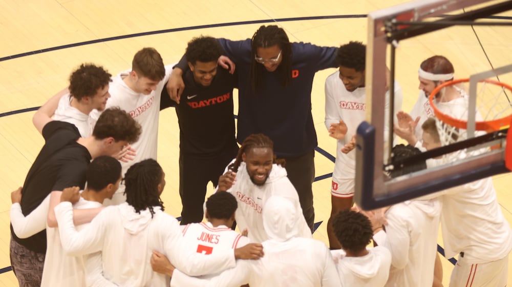 Dayton's Jaiun Simon dances in the middle of a team huddle before a game against George Washington on Tuesday, Jan. 6, 2026, at UD Arena. David Jablonski/Staff