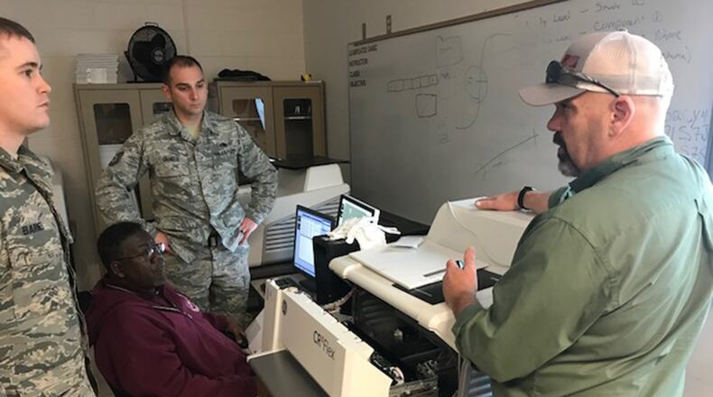 Kevin McClain, contract nondestructive testing instructor, explains how to clear a jammed image scanner from a computed radiography system to visiting Nondestructive Inspection Instructor, Tech. Sgt. Matthew Barnes (left); Tech. Sgt. Clifford Daniels, Military NDI Instructor supervisor (rear); and Bobby Britton, civilian NDI Instructor supervisor (seated) during instructor qualification training held at the 359th Training Squadron Detachment One at Naval Air Station Pensacola, Fla., Jan. 24. New digital technology will replace the X-ray film used by NDI technicians over the next several years and impact every airframe the Air Force flies, saving money, reducing hazardous materials and improving operational capabilities. (Courtesy photo)