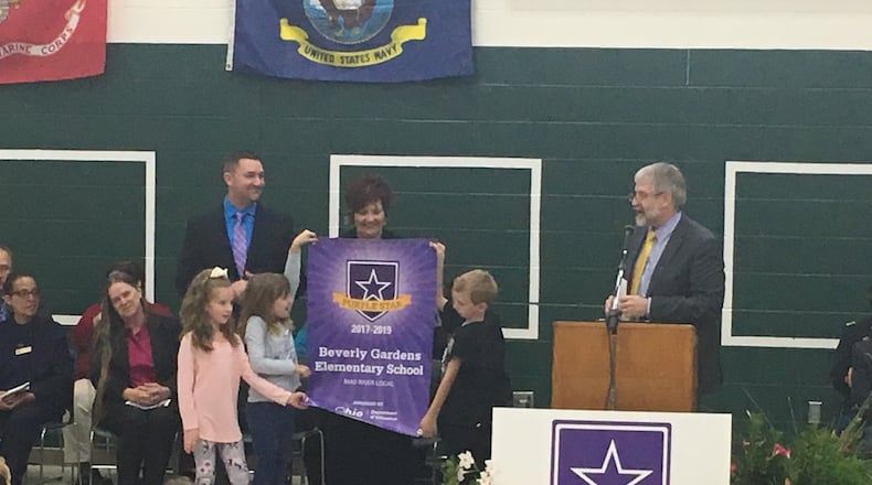 Students at Beverly Gardens Elementary unfurl a new banner recognizing them as a Purple Star military-friendly school, while state schools superintendent Paolo DeMaria (right) speaks to students. JEREMY P. KELLEY / STAFF