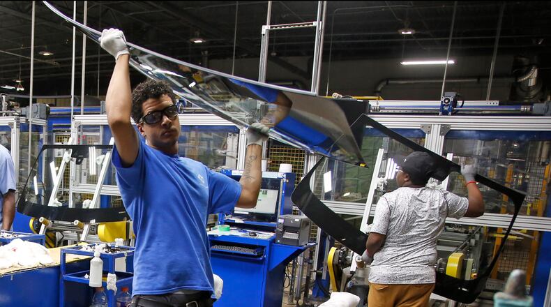 Workers at Fuyao Glass America finish an automobile windshield in the Moraine plant. Fuyao employs 2,300 workers and expects to need 700 more within three years. TY GREENLEES / STAFF