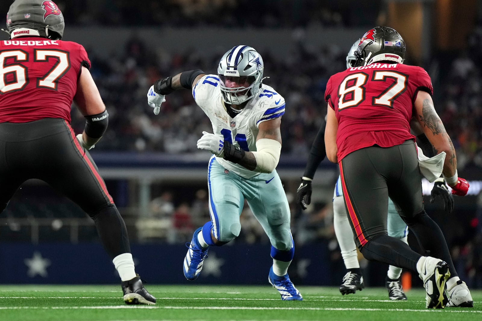 FILE - Dallas Cowboys linebacker Micah Parsons (11) rushes against Tampa Bay Buccaneers offensive tackle Luke Goedeke (67) and tight end Payne Durham (87) during the second half of a football game Sunday, Dec. 22, 2024, in Arlington, Texas. (AP Photo/Jeffrey McWhorter, File)