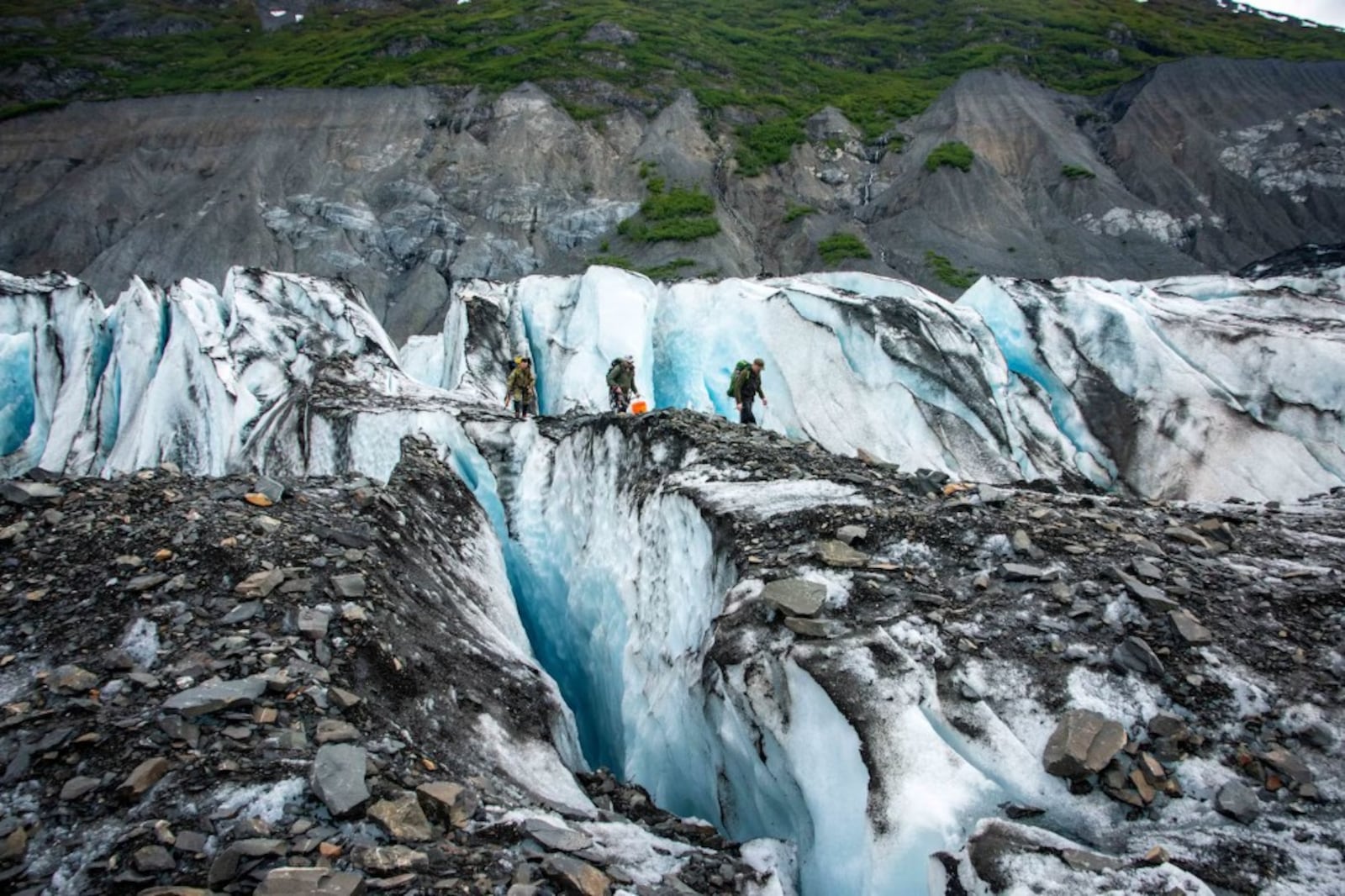 Recovery team members cross a glacier ridge returning to the landing zone after a day of recovering possible human remains, personal effects and equipment at Colony Glacier, Alaska, June 16, 2023. Operation Colony Glacier is an effort to recover the remains of service members and wreckage from a C-124 Globemaster II that crashed in November 1952 with 52 military members on board. Following the inventory of items found, an honorable carry and dignified departure for the remains is conducted by the Joint Base Elmendorf-Richardson Honor Guard and 673rd Medical Group personnel before being escorted to Dover Air Force Base, Del. CREDIT: U.S. Department of War