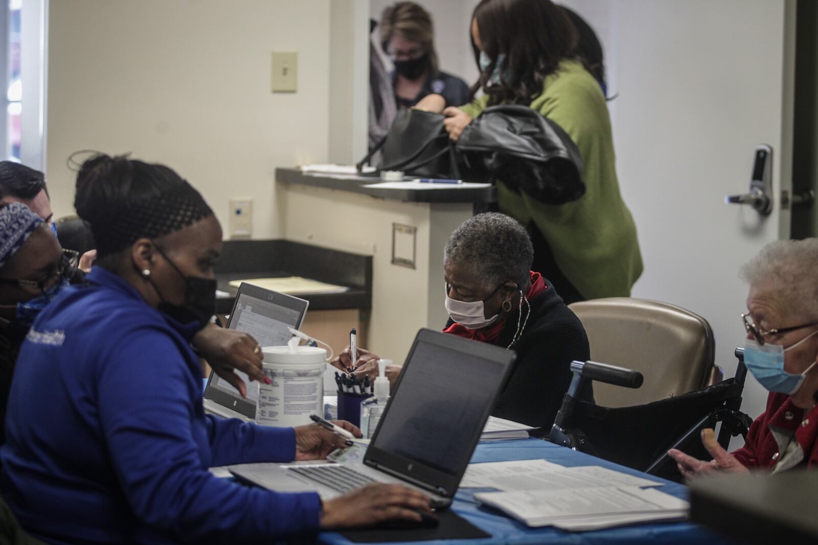 People fill out paperwork Tuesday morning prior to receiving a COVID-19 vaccine at the Foraker Street Clinic. JIM NOELKER/STAFF
