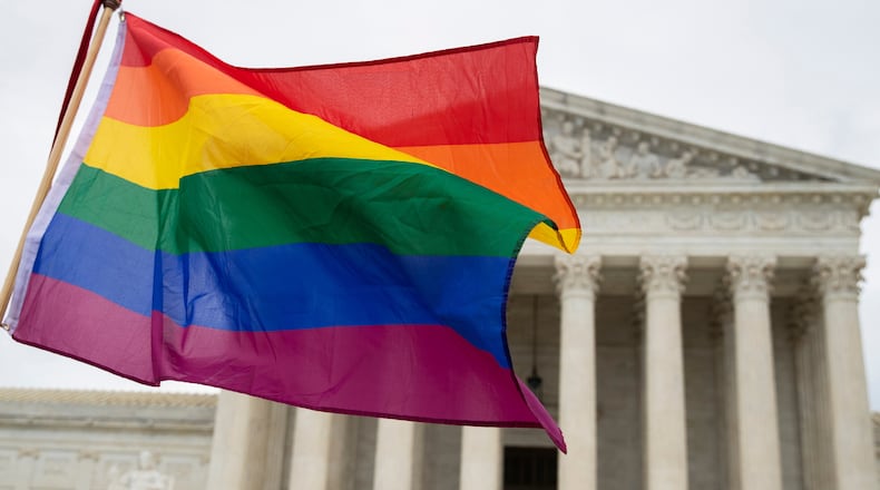 FILE - Supporters of the LGBT wave their flag in front of the U.S. Supreme Cour, Oct. 8, 2019, in Washington. (AP Photo/Manuel Balce Ceneta, File)