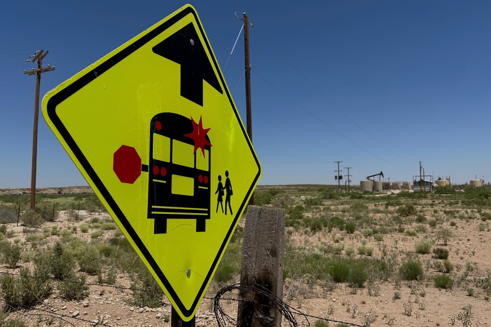 A sign warns drivers of a school bus stop near an oilfield, on the outskirts of Loving, N.M., on Tuesday, May 19, 2025. (AP Photo/Susan Montoya Bryan)