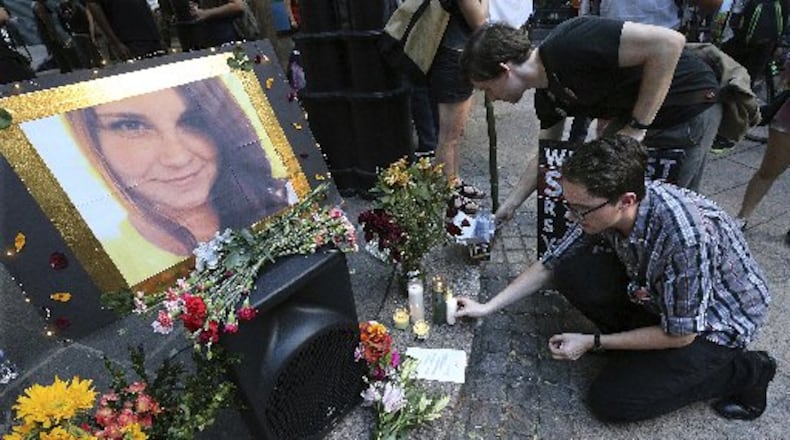 Stephen Friedrich, front, and Scott Douglas set out candles for Heather Heyer as hundreds gather at Woodruff Park on Sunday, Aug. 13, 2017, in Atlanta. Protesters decrying hatred and racism converged around the country on Sunday, saying they felt compelled to counteract the white supremacist rally that spiraled into deadly violence in Virginia. (Curtis Compton/Atlanta Journal-Constitution via AP)