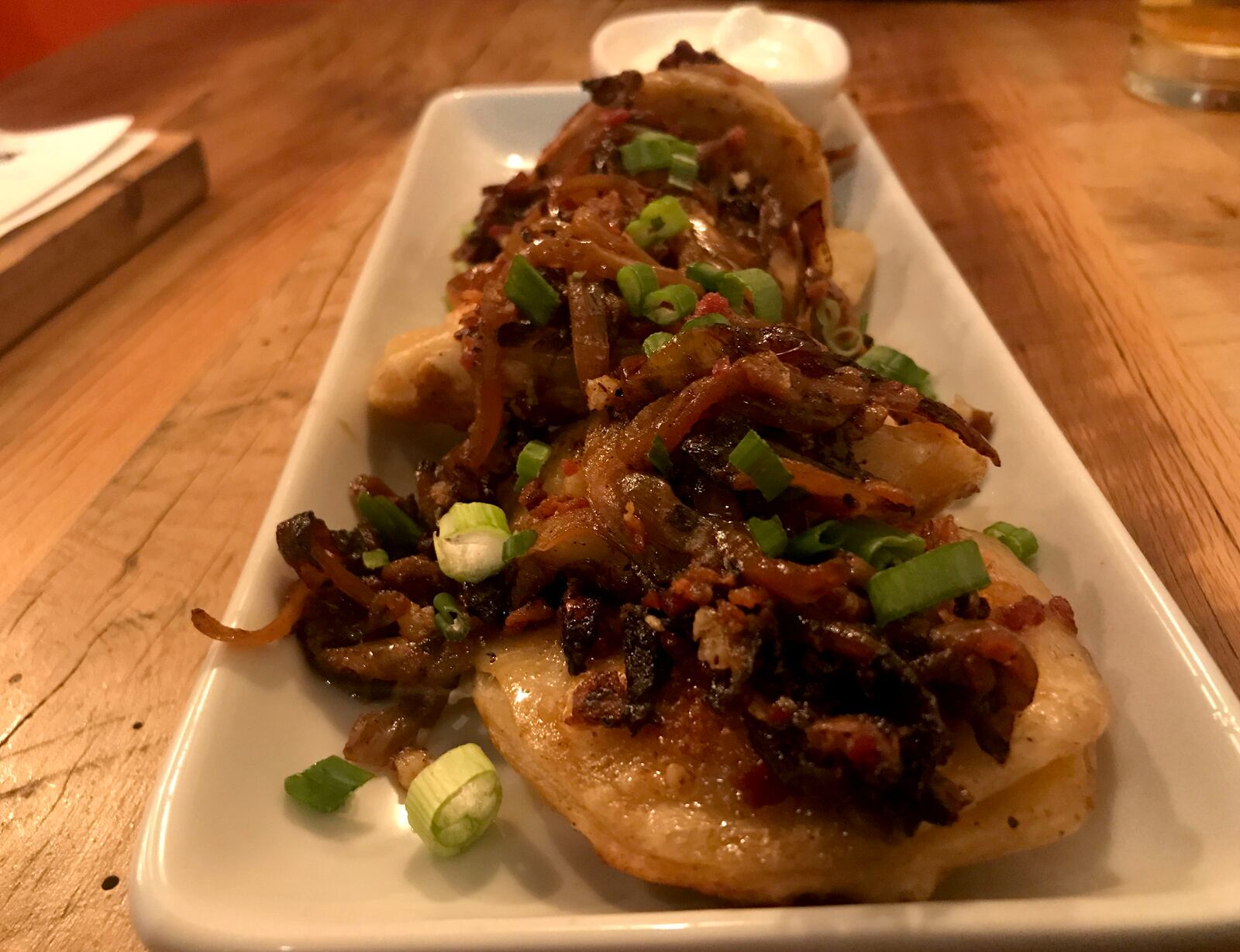 The food at Lock 27 in downtown Dayton. Pictured: 
Potato and cheddar pierogies topped with bacon, sautéed onions and garlic.  They are served with  sour cream. Photo by Amelia Robinson