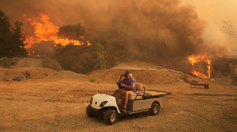 FILE - A resident rides a golf cart as he exits his property while the Canyon Fire burns on Aug. 7, 2025, in Hasley Canyon, Calif. (AP Photo/Marcio Jose Sanchez, File)