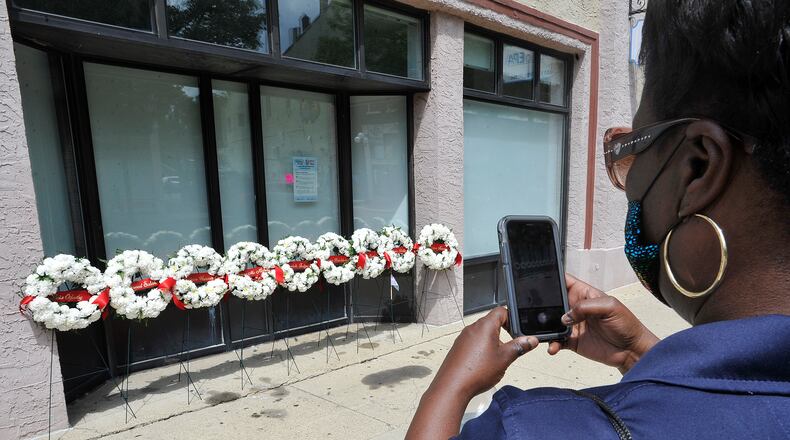 A passerby takes photos of the wreaths for the nine victims in the 2019 Oregon District shooting. MARSHALL GORBY\STAFF
