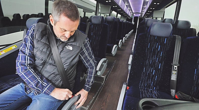 Buckeye Charters, president Jerry Biedenharn, demonstrates the seatbelt on his companies newest motor coach bus. Staff Photo Marshall Gorby