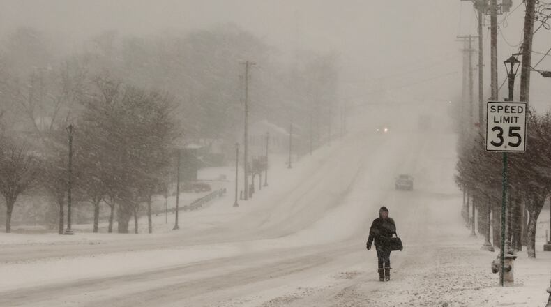 A woman walks in the snow along Main Street in Englewood on Thursday afternoon, Feb. 3, 2022. After sleet and freezing rain fell, snow finally arrived. BILL LACKEY/STAFF