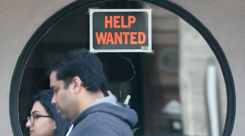 FILE - Pedestrians walk past a help wanted sign posted on the door of a restaurant in San Francisco, Tuesday, April 18, 2023. (AP Photo/Jeff Chiu, File)