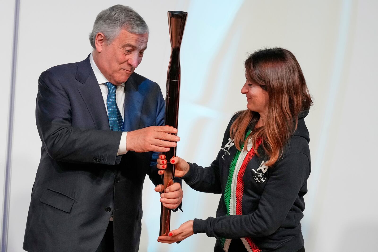 Italian Deputy Prime Minister and Foreign Minister Antonio Tajani, left, passes the torch for the Olympic and Paralympic Winter Games Milano Cortina 2026 to Italian figure skater Valentina Marchei during the official unveiling ceremony at Italian Pavilion of Osaka Expo 2025 in Osaka, western Japan, Monday, April 14, 2025. (AP Photo/Hiro Komae)