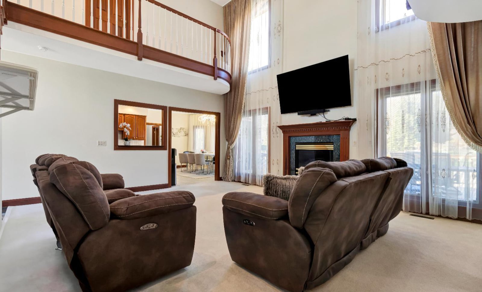 The two story great room has a gas fireplace and a ceiling fan, neutral carpeting and exterior doors opening to the back deck. CONTRIBUTED