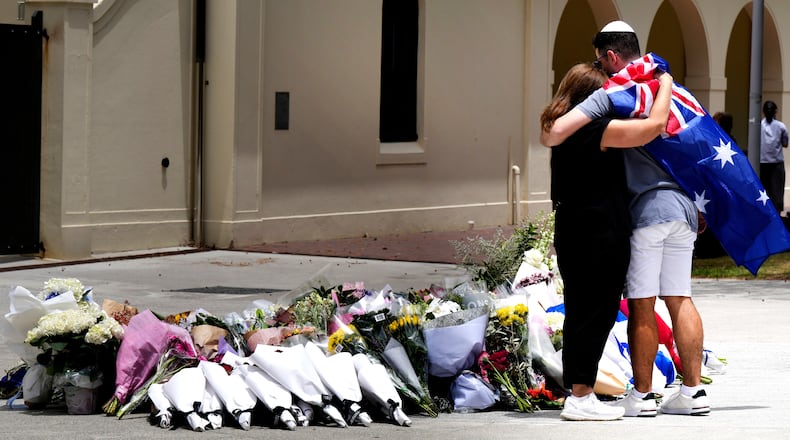 A couple lay flowers at a tribute to shooting victims outside the Bondi Pavilion at Sydney's Bondi Beach, Monday, Dec. 15, 2025, a day after a shooting. (AP Photo/Mark Baker)