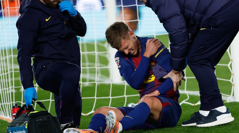 Barcelona's Dani Olmo reacts in pain in his arm after scoring his side's second goal during a Spanish La Liga soccer match between Barcelona and Atletico de Madrid, in Barcelona, Spain, Tuesday, Dec.2, 2025. (AP Photo/Joan Monfort)