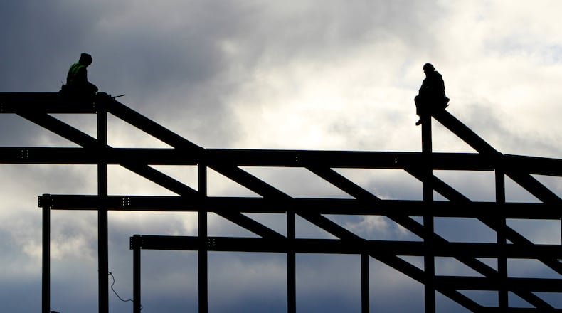 Construction crews perched high atop the metal bones of the building in downtown Dayton. CORNELIUS FROLIK / STAFF